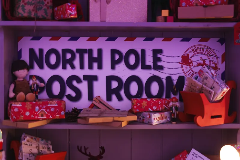 The North Pole Post Room sign on a shelf of wrapped presents and letters